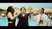 a group of women standing next to a pool drinking beer