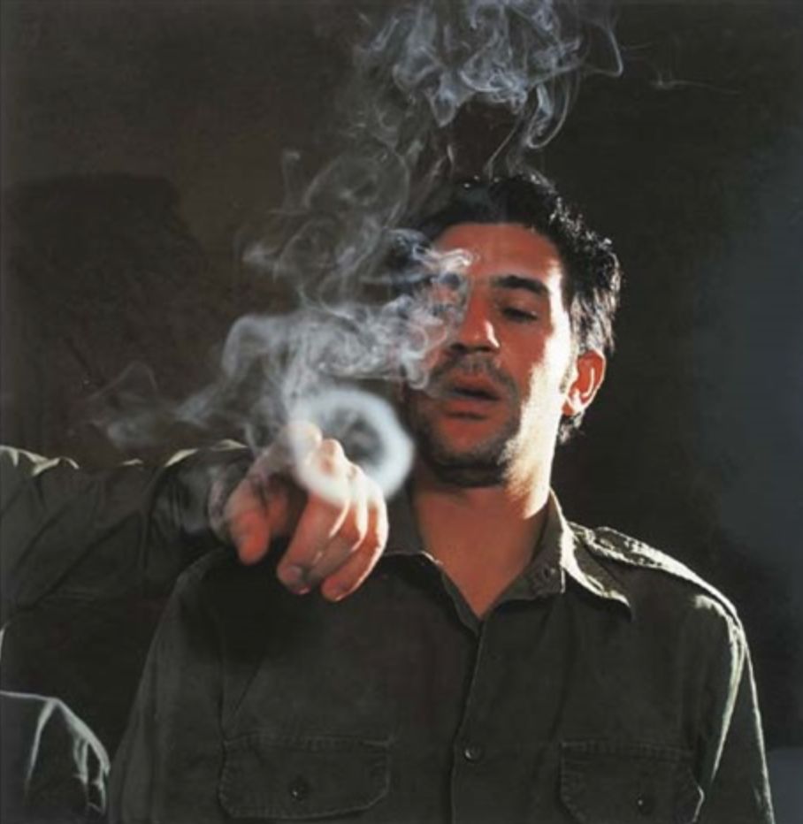 a man smoking a cigarette in a dark room