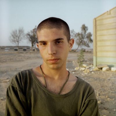 a man standing in a dirt field next to a building