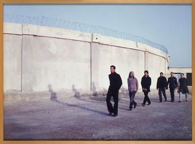 a group of people walking in front of a wall