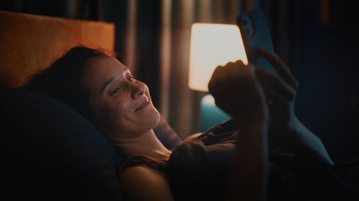 a woman laying on a bed looking at a tablet