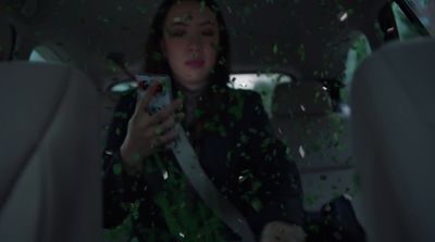 a woman sitting in the back seat of a car holding a cell phone