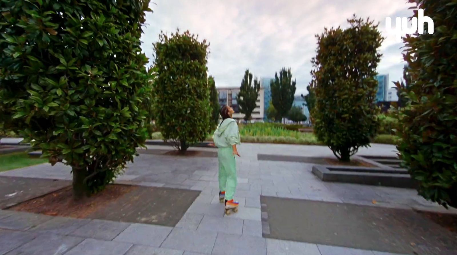 a woman in a long green dress walking through a park