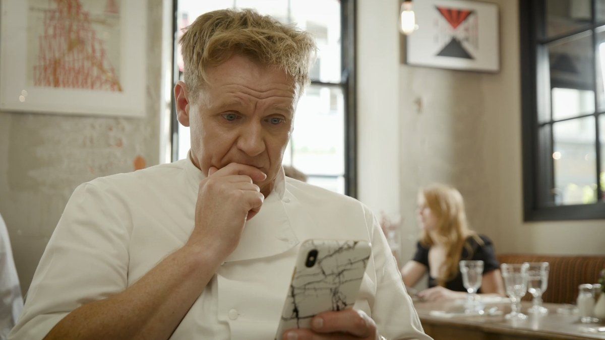 a man sitting at a table looking at a cell phone