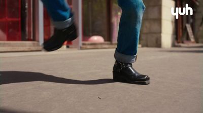 a person wearing black shoes walking down a street