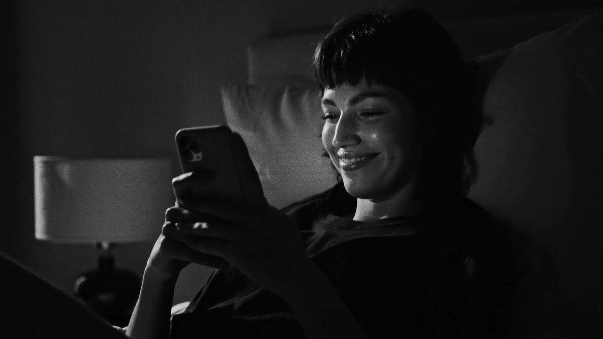 a woman sitting on a bed looking at a cell phone