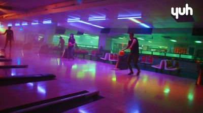 a group of people standing around a bowling alley