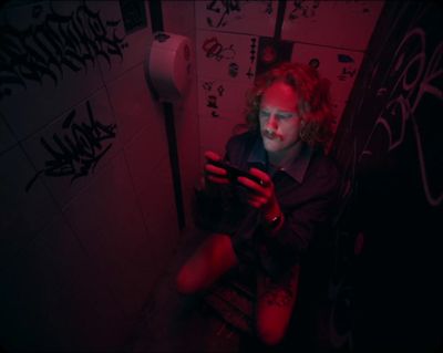 a man sitting on a toilet using a cell phone
