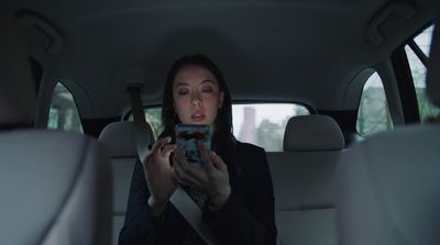 a woman sitting in the back seat of a car looking at a cell phone