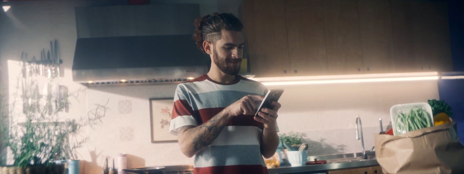 a man standing in a kitchen looking at a cell phone