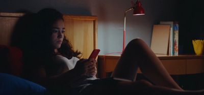 a woman sitting on a bed looking at a cell phone