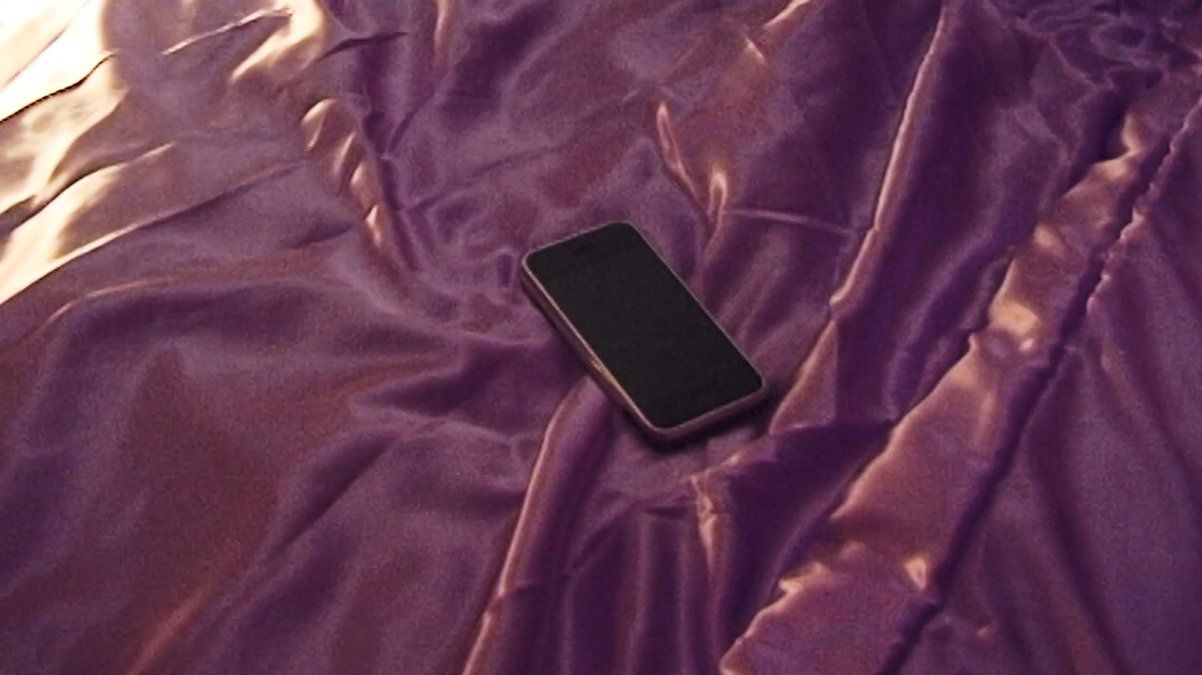 a cell phone laying on a purple sheet