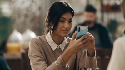 a woman sitting at a table looking at her cell phone