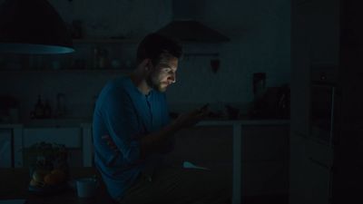 a man sitting in the dark looking at his cell phone