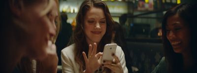 a group of women sitting around each other looking at a cell phone