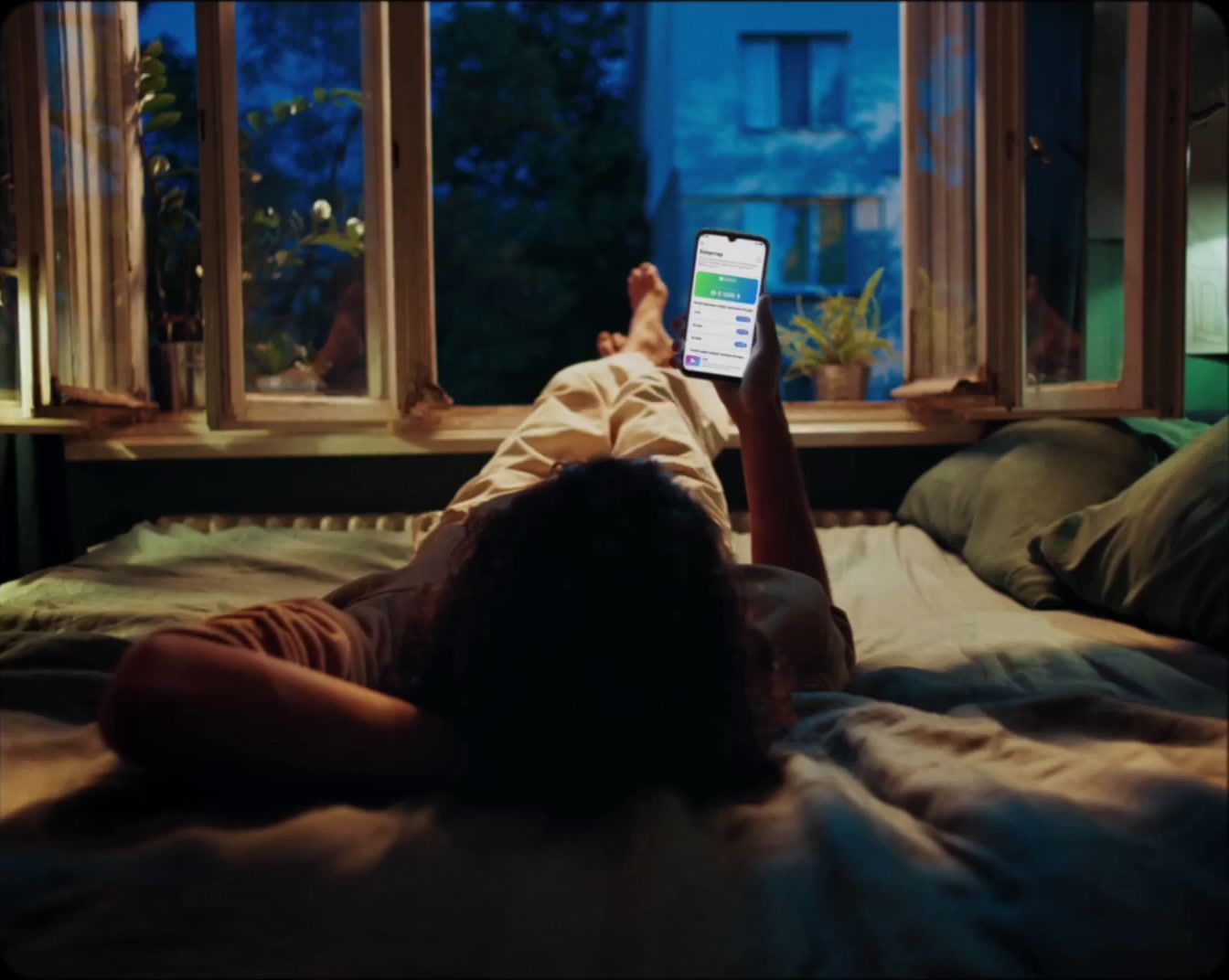 a person laying on a bed looking at a cell phone