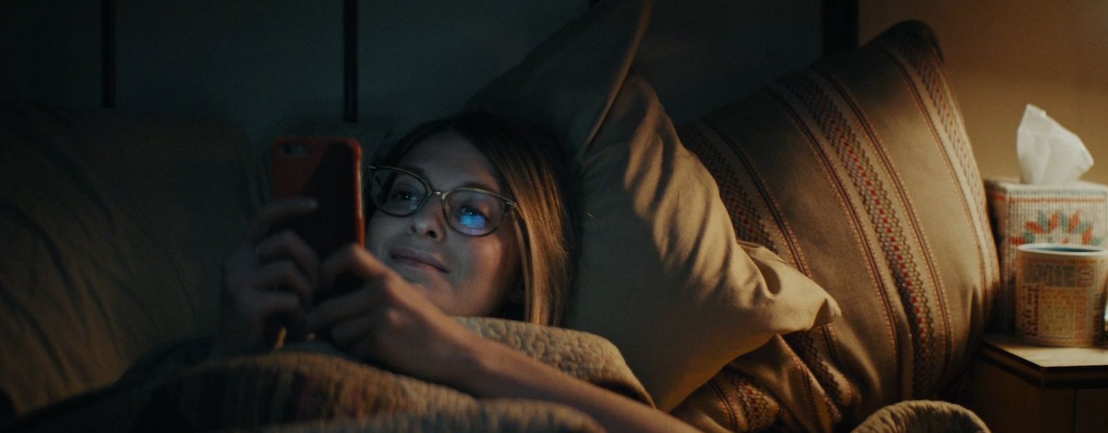 a woman laying in bed looking at her cell phone