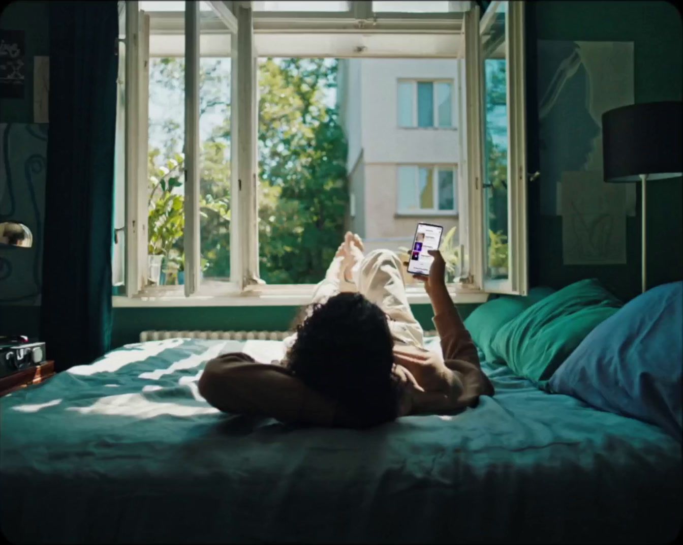 a woman laying on a bed looking at a cell phone