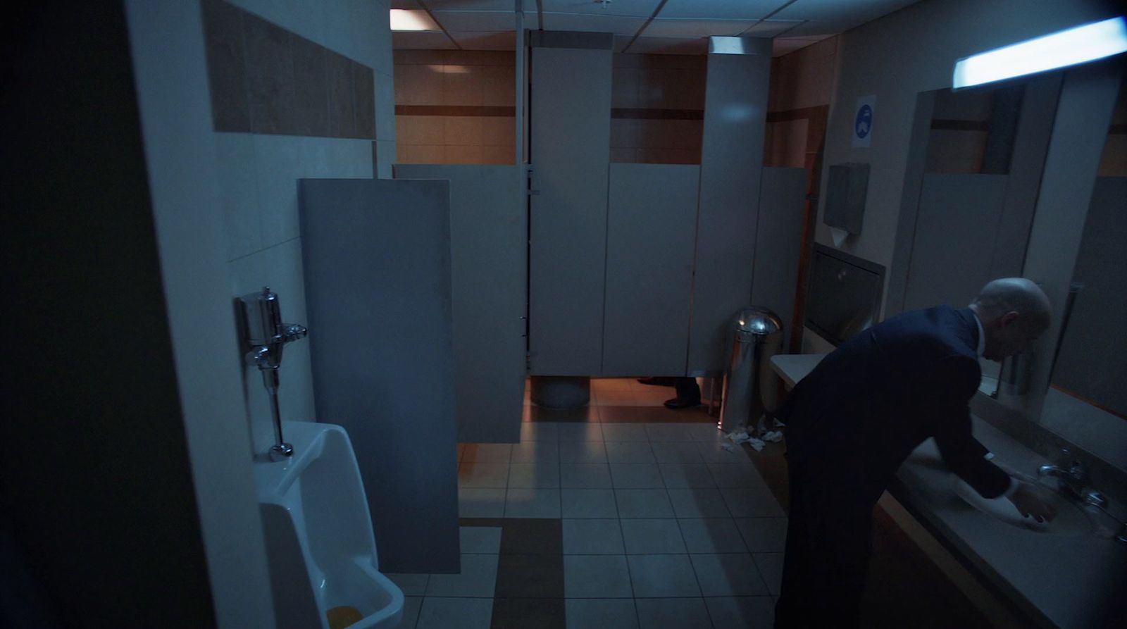 a man standing in a bathroom next to a urinal