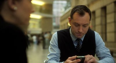 a man sitting at a table looking at a cell phone