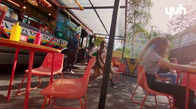 a group of people sitting at a table in front of a bus