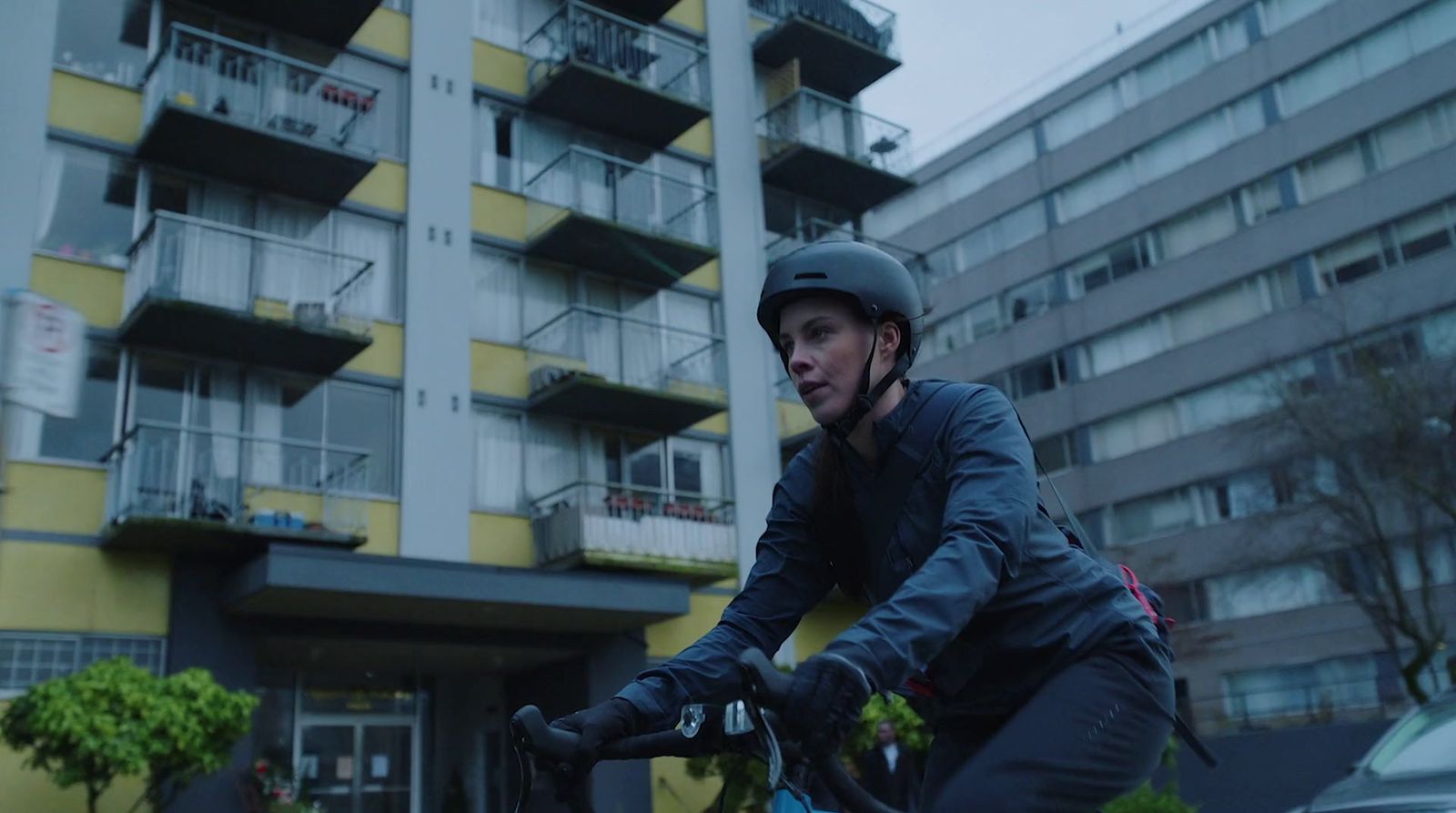 a man riding a bike in front of a tall building