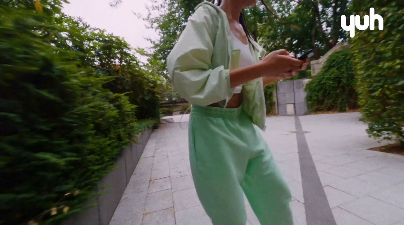 a woman standing on a sidewalk holding a cell phone