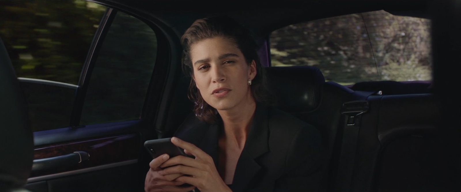 a woman sitting in a car looking at her cell phone