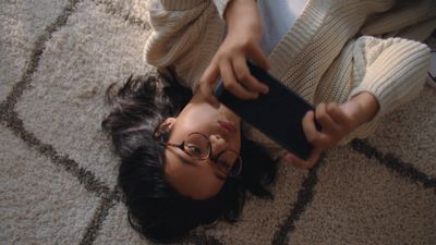 a woman laying on the floor holding a cell phone