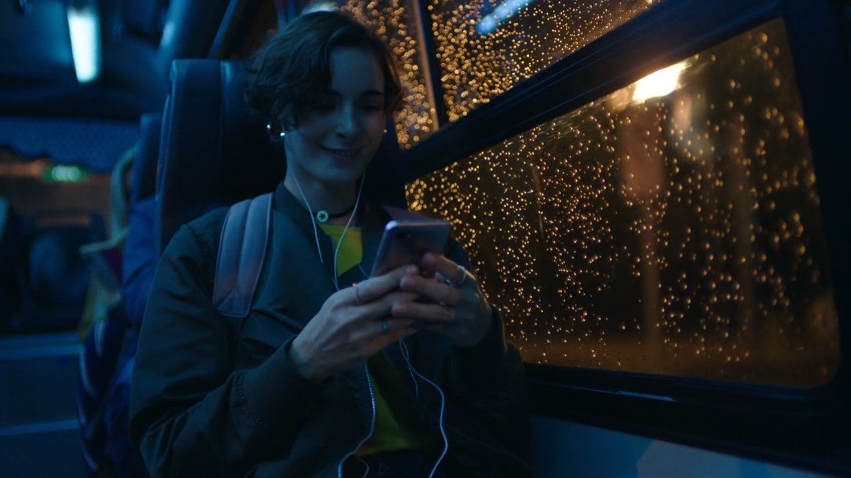 a person sitting on a bus looking at a cell phone