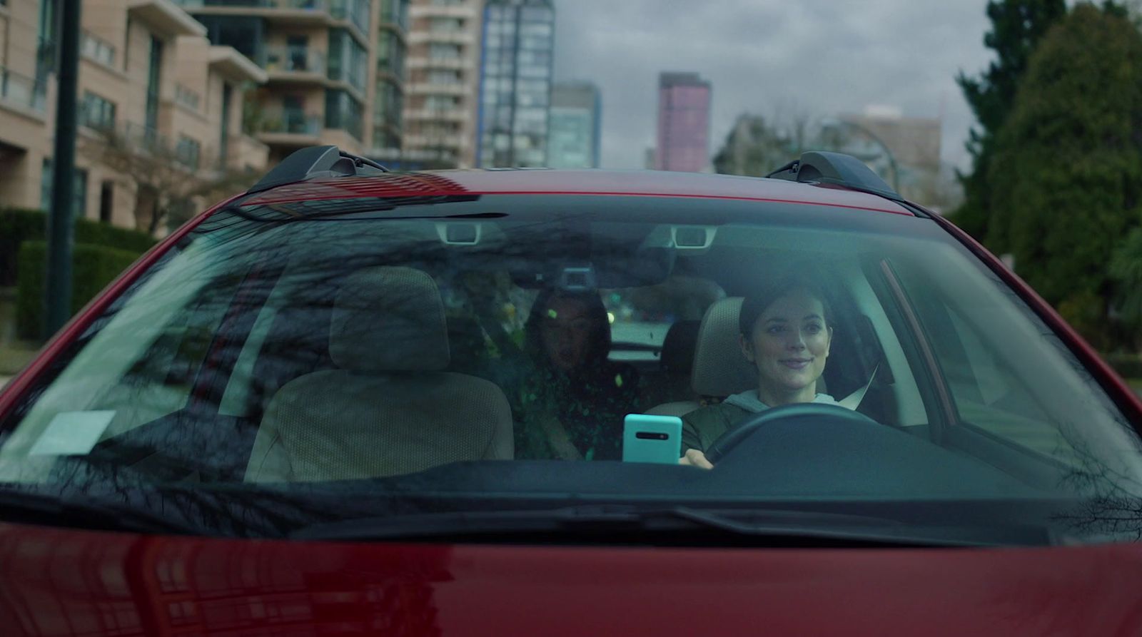 a woman sitting in a car with a cell phone in her hand