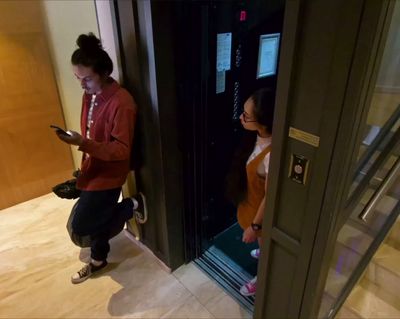 a woman standing in a doorway looking at her cell phone