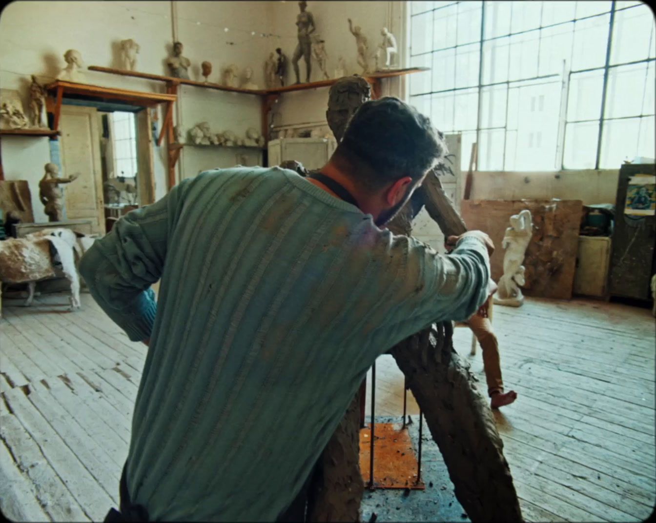 a man standing in a room with a wooden floor