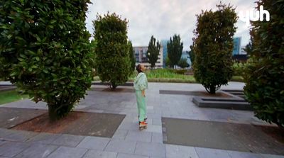 a man in a green suit walking through a park