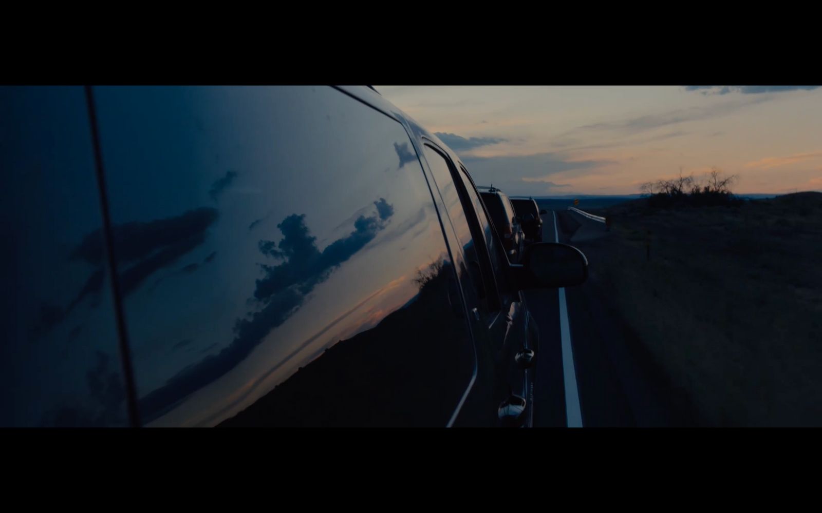 a car driving down a road next to a field