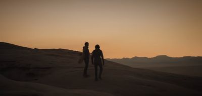 a couple of people standing on top of a desert