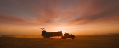 a couple of trucks driving down a dirt road