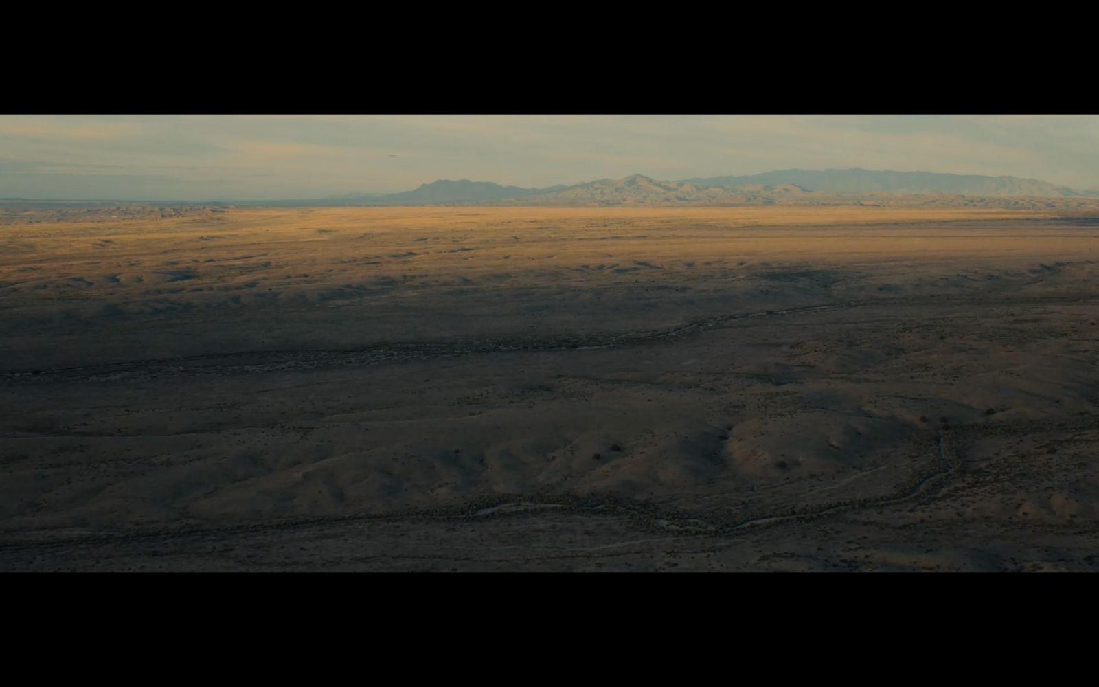 an aerial view of a plain with mountains in the distance