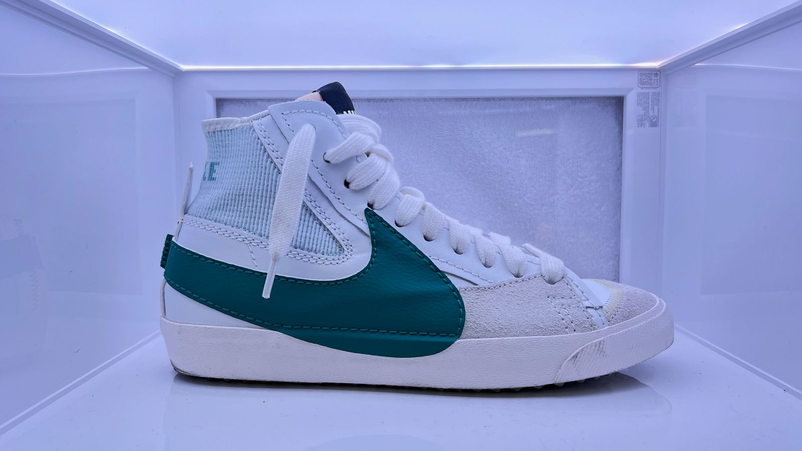 a pair of white and green sneakers in a display case