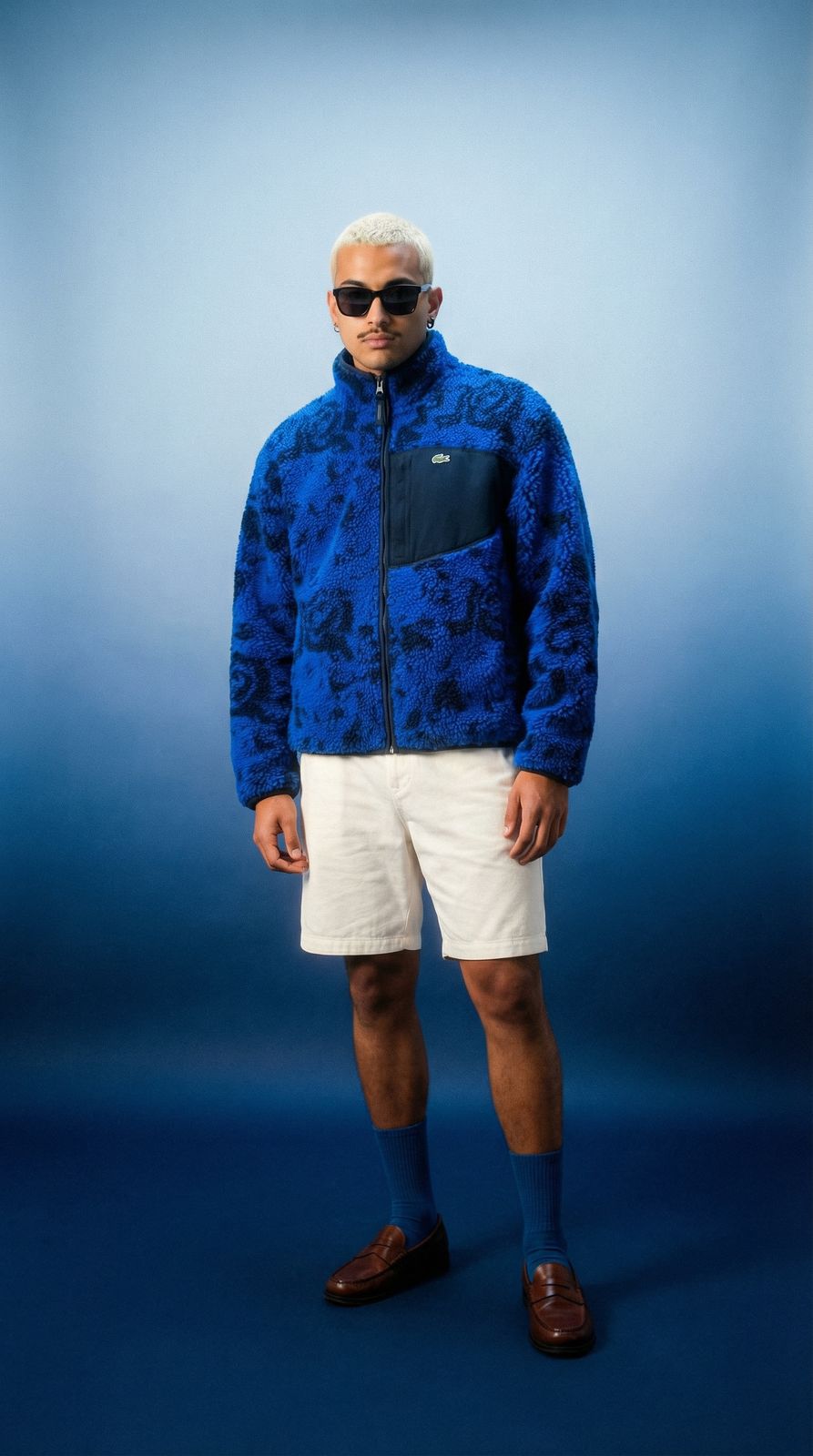 a man in a blue jacket and white shorts