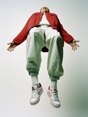 a man in a red jacket and green pants jumping in the air