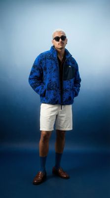 a man in a blue jacket and white shorts