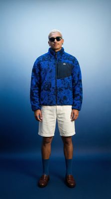 a man in a blue jacket and white shorts