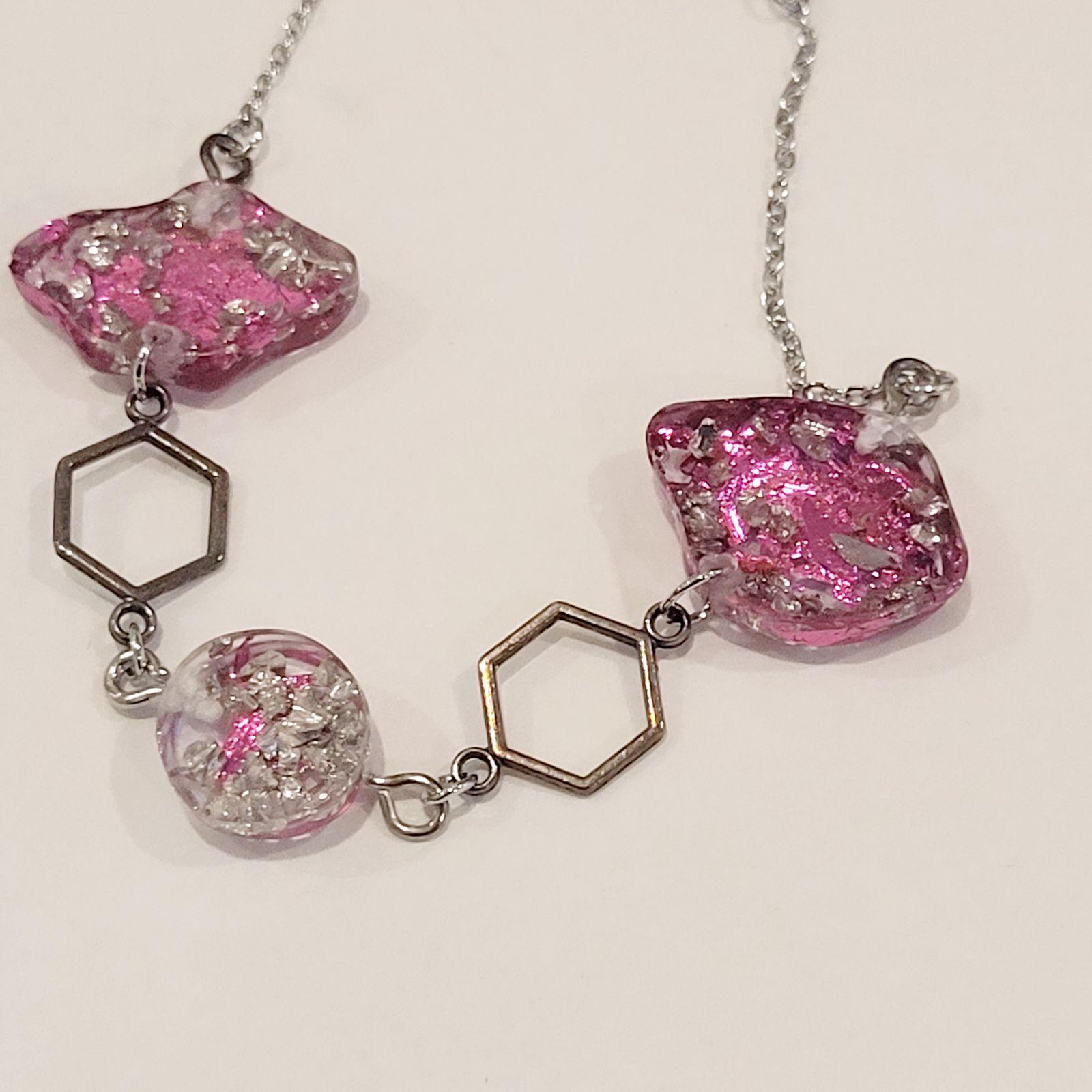 a necklace with pink and silver beads on a white surface