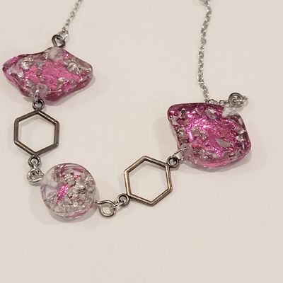 a necklace with pink and silver beads on a white surface