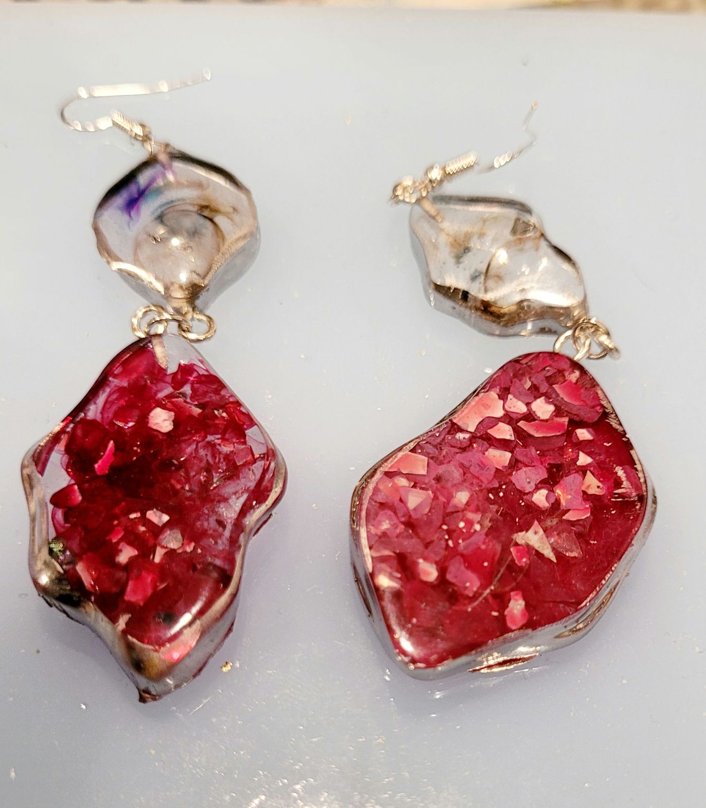 a pair of red and silver earrings on a white surface