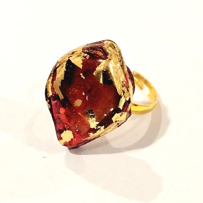a gold ring with a large red stone in it