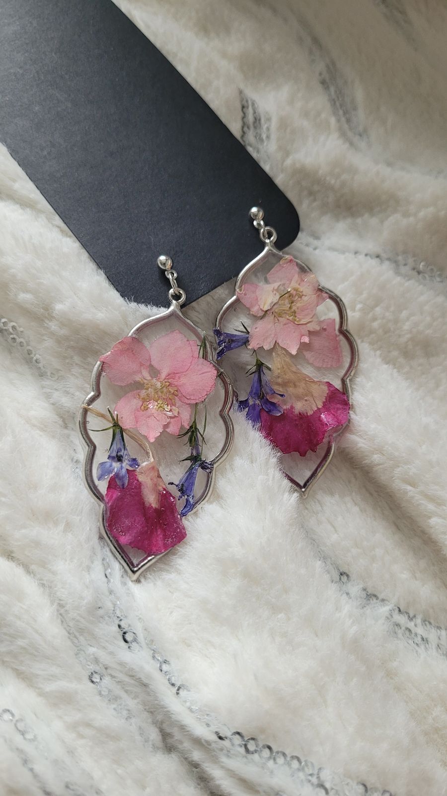 a pair of pink flowers are hanging from a pair of earrings