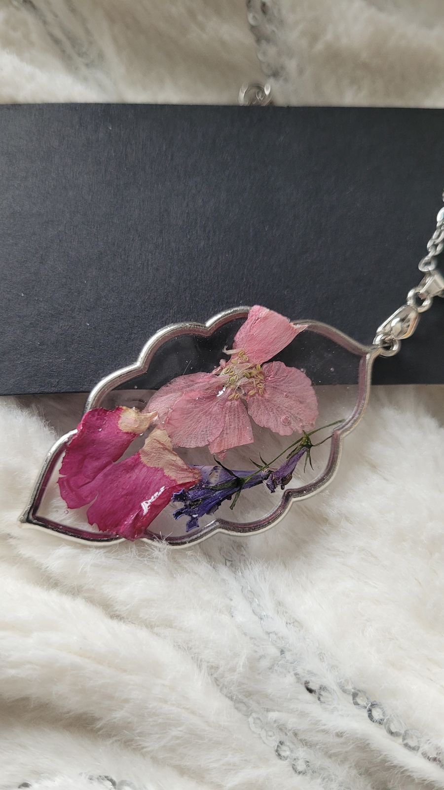 a pink flower in a glass vase on a chain