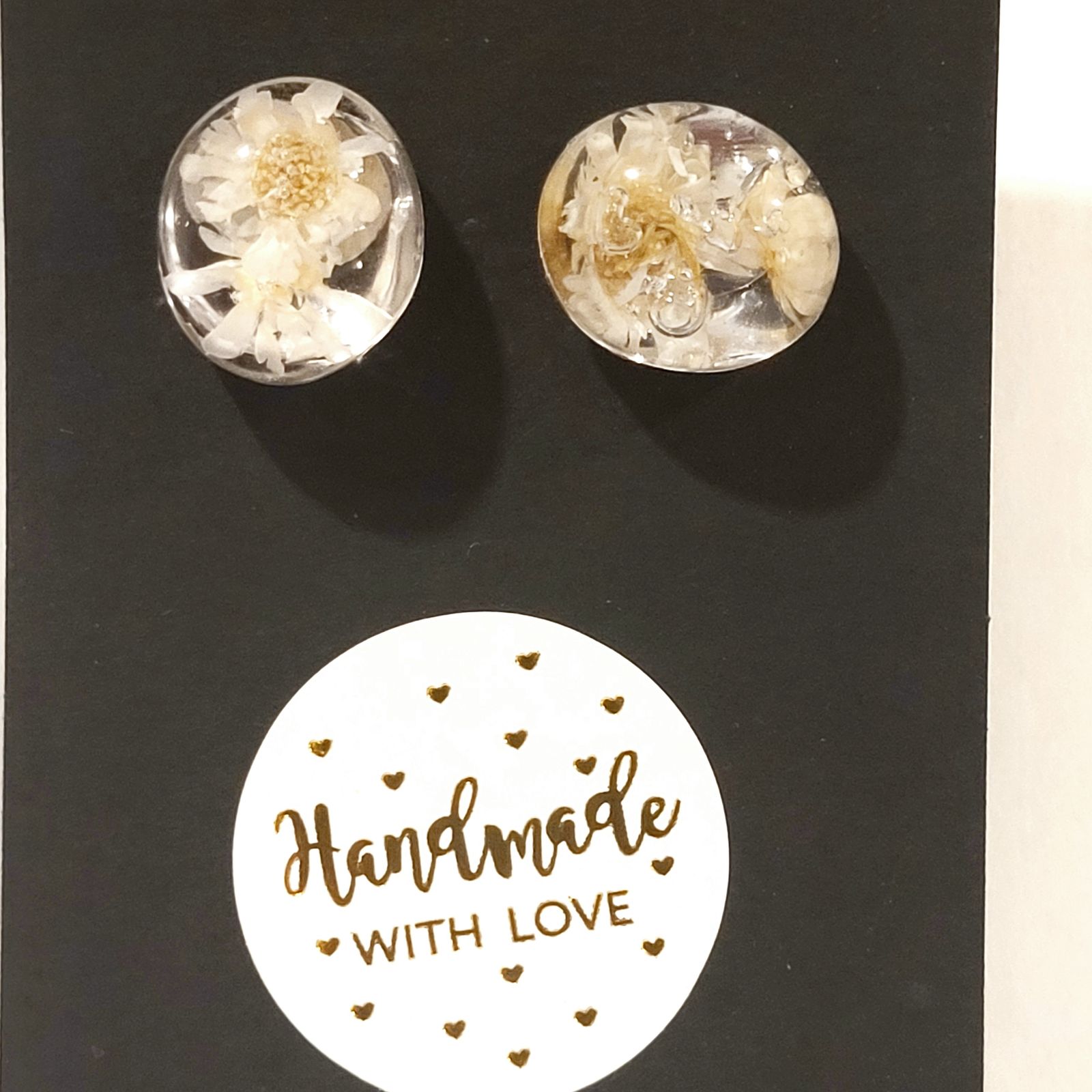 a pair of earrings with white flowers on a black background